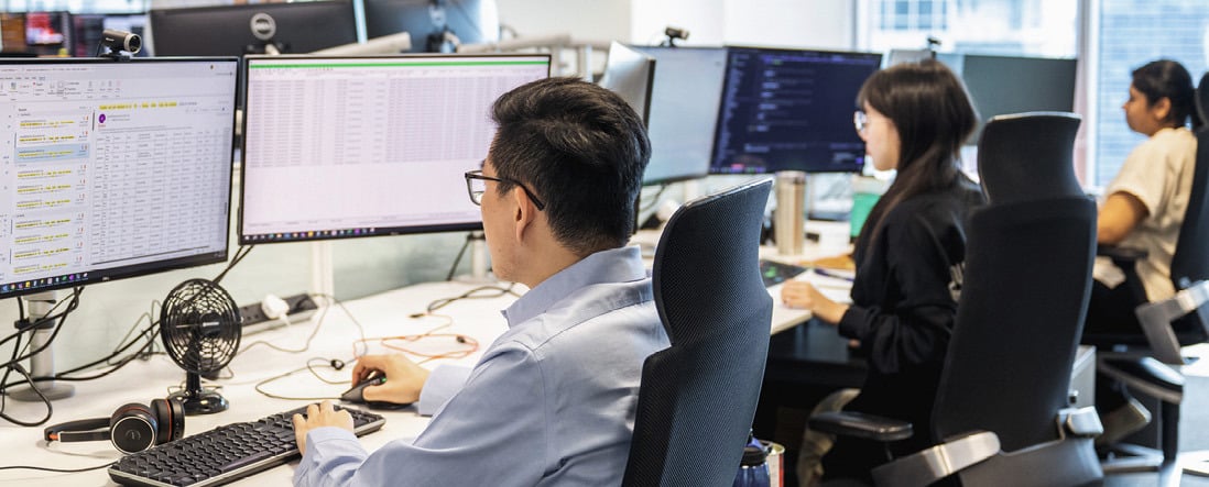 Three employees working at their desks in Norges Bank Investment Management's Singapore office.
