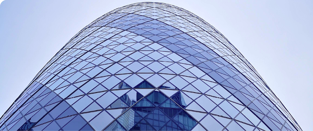 Close-up of a modern glass office building with a curved façade and geometric pattern.