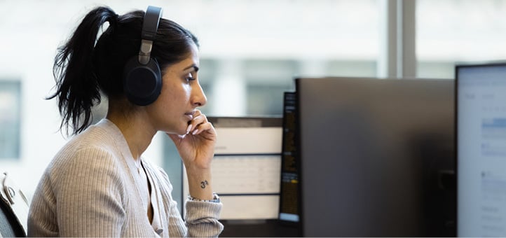 Employee working at a computer with headphones on at the New York office.