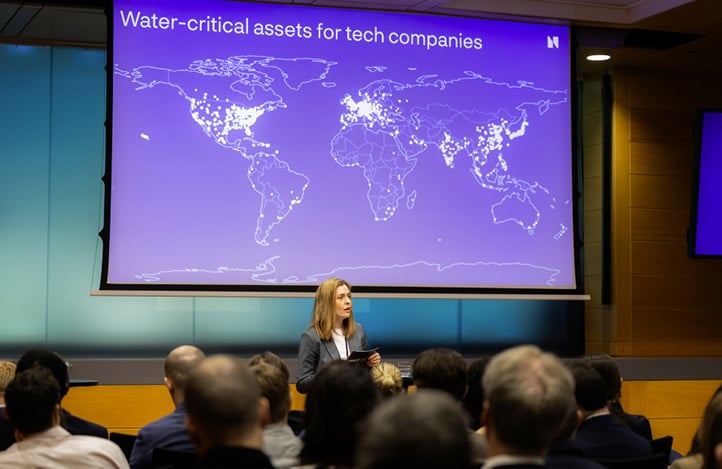 Presenter speaking in front of a slide titled “Water-critical assets for tech companies,” showing a world map with highlighted locations.