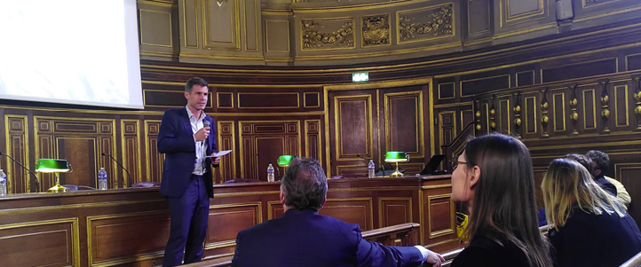 Man speaking at the FIR–PR Awards Ceremony at the Sorbonne University in Paris, with audience seated in a historic hall.