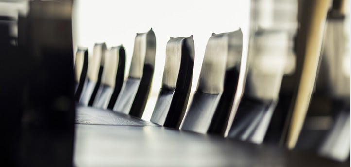 Row of empty chairs along a conference table.