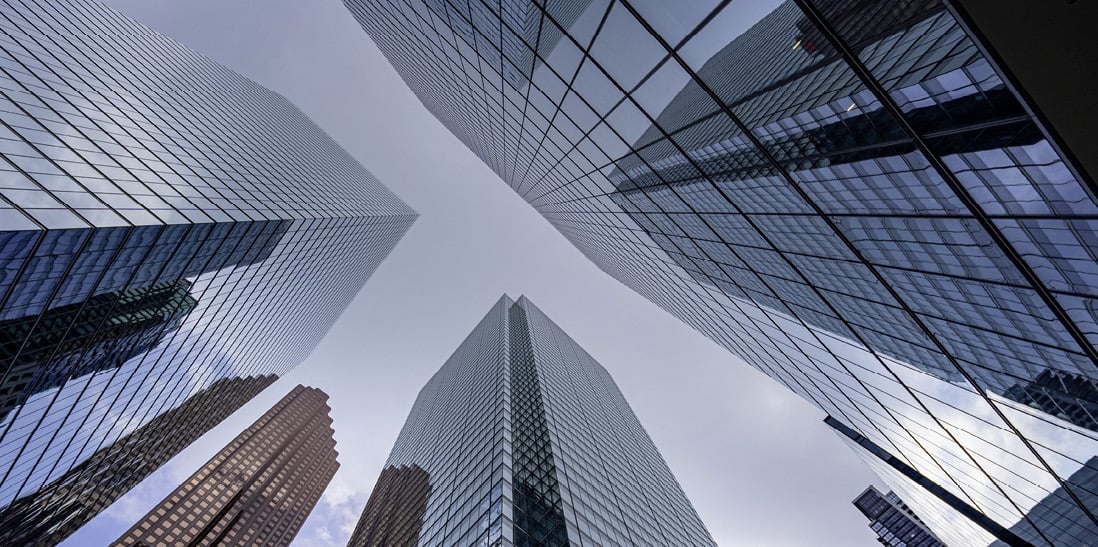 View looking up at modern glass skyscrapers in a city.