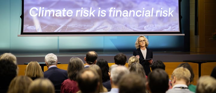 Innleder som holder innlegg foran en presentasjon med teksten &laquo;Climate risk is financial risk&raquo;.