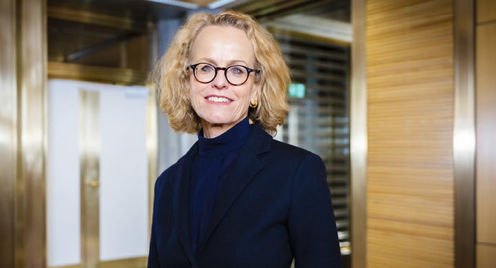 A woman wearing a black jacket and glasses is standing in a hallway.

AI generated content