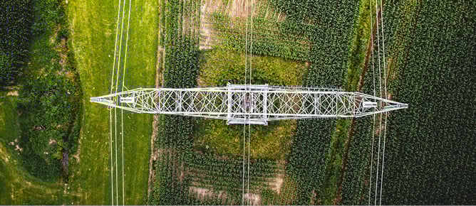 Luftfoto av h&oslash;yspentmast over jordbruksomr&aring;der.